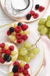 Photo of Delicious tartlets with berries on white wooden table, flat lay