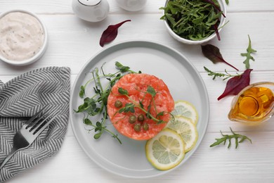 Tasty salmon tartare with lemon, capers and microgreens served on white wooden table, flat lay