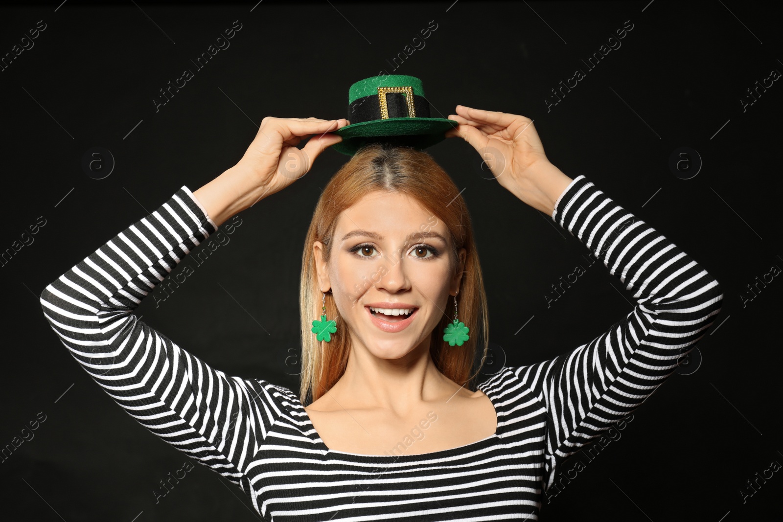 Photo of Young woman with green leprechaun hat on black background. St. Patrick's Day celebration