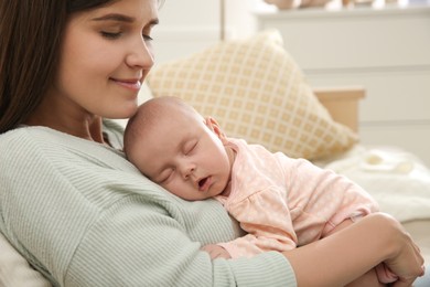 Photo of Mother holding her sleeping baby at home