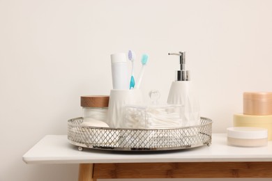 Photo of Different bath accessories and personal care products on table near white wall