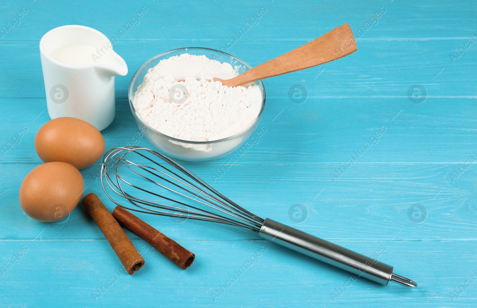 Photo of Raw eggs and other ingredients on light blue wooden table. Baking pie