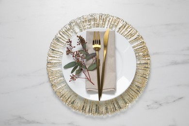 Photo of Stylish setting with cutlery and eucalyptus leaves on white marble table, flat lay