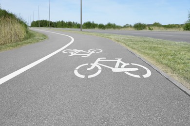 Photo of Bicycle lane with white sign painted on asphalt near sidewalk