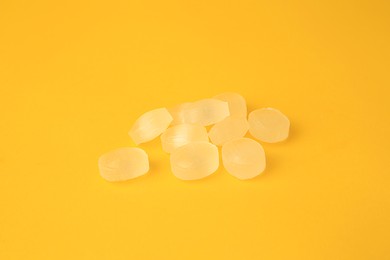 Photo of Many yellow cough drops on orange background