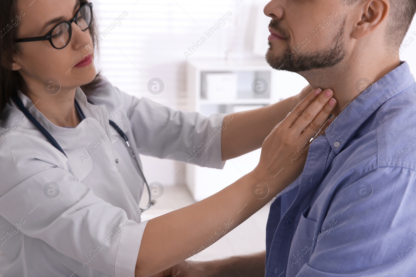 Photo of Doctor examining thyroid gland of patient in hospital, closeup