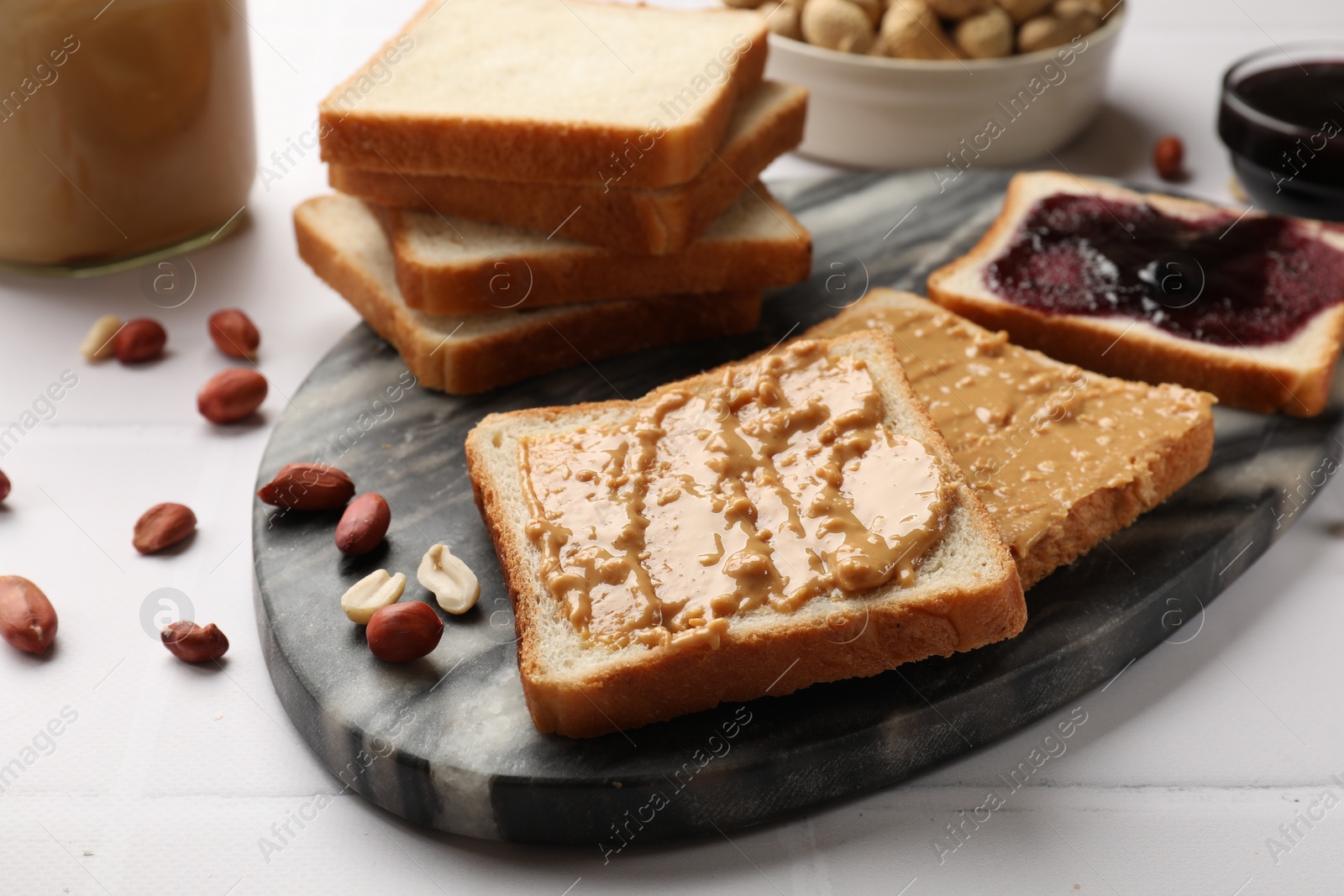 Photo of Delicious toasts with peanut butter, nuts and jam on white table