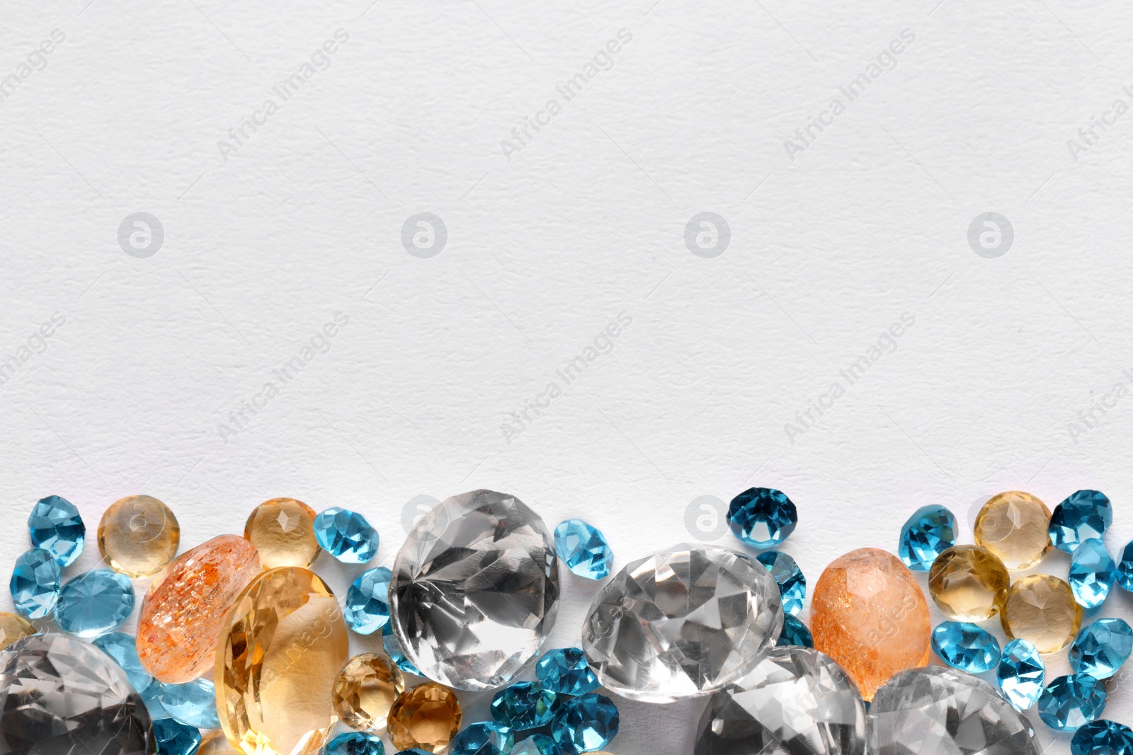 Photo of Different beautiful gemstones for jewelry on white background, top view. Space for text