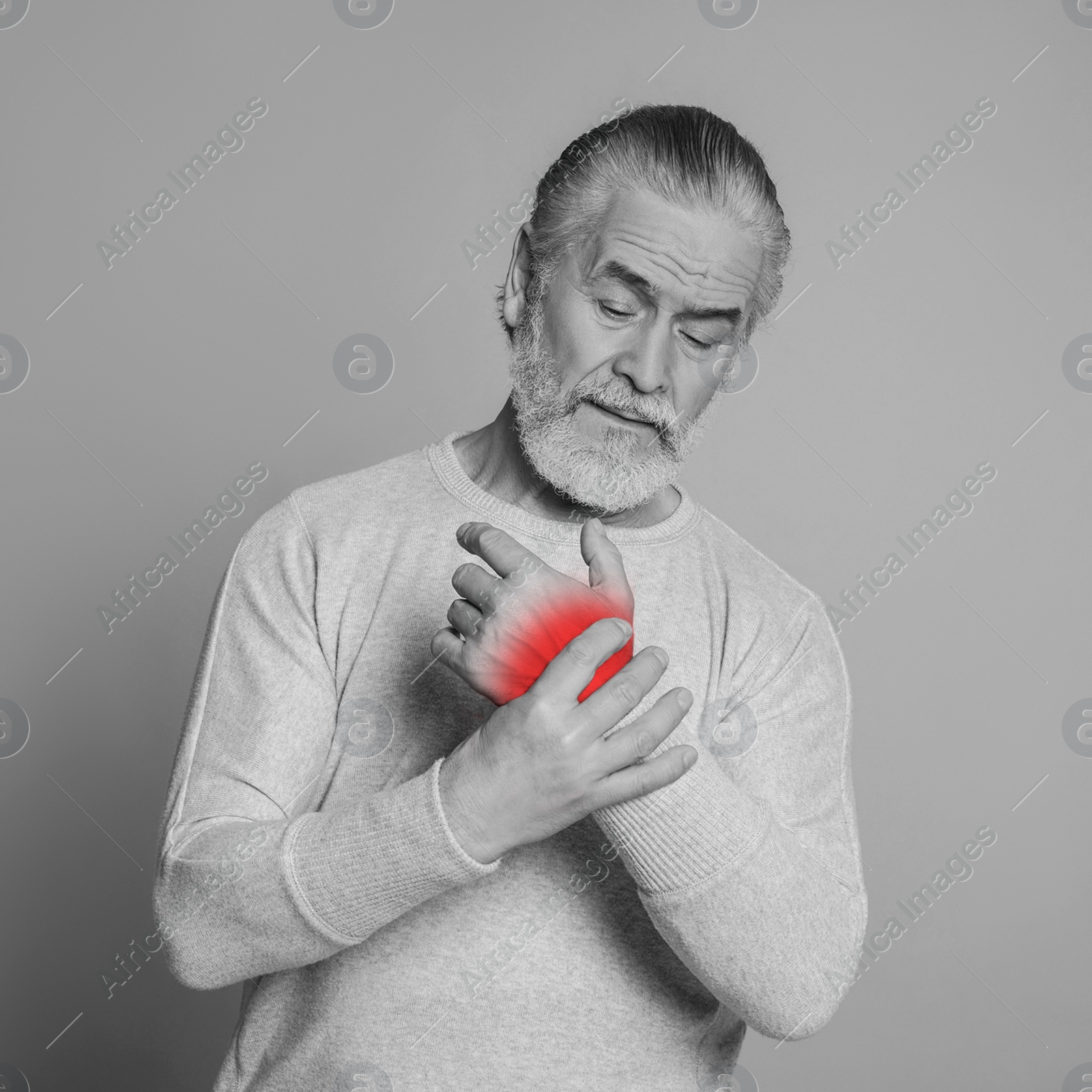 Image of Senior man suffering from rheumatism on light background. Black and white effect with red accent in painful area