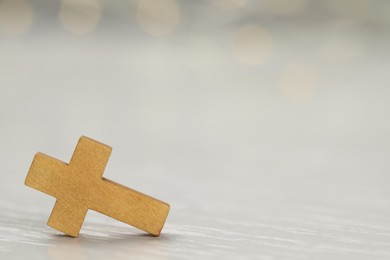 Christian cross on white wooden table, closeup. Space for text