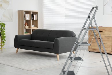 Photo of Metal folding ladder in stylish living room