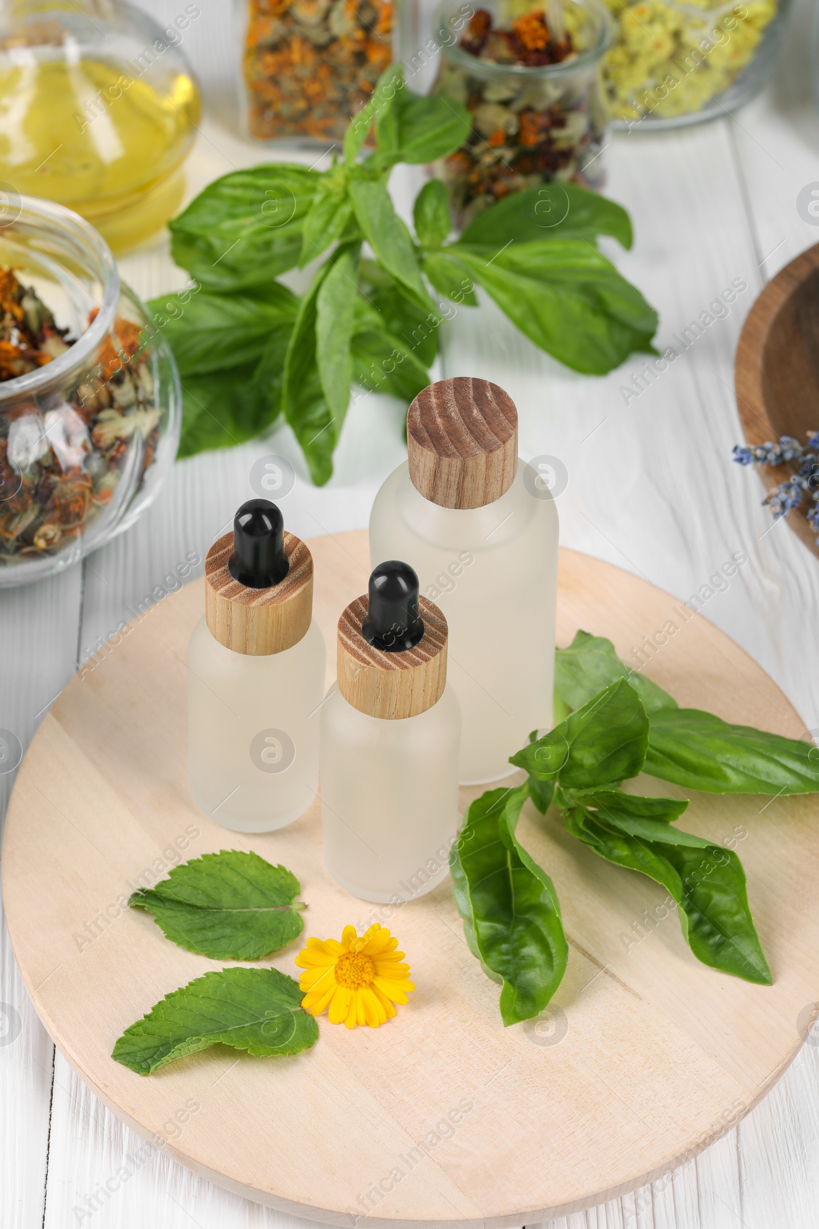 Photo of Herbal medicine. Bottles of essential oils, leaves and flower on white wooden table