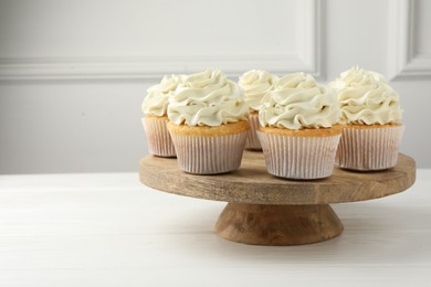 Photo of Tasty vanilla cupcakes with cream on white wooden table, space for text