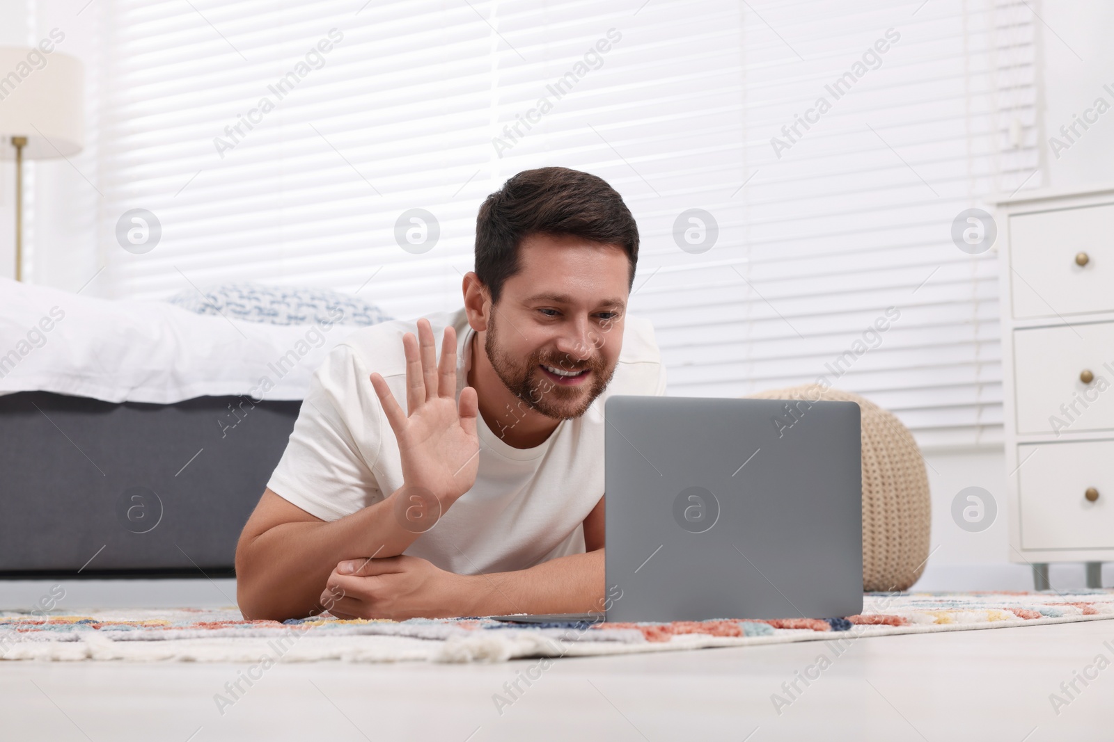 Photo of Happy man greeting someone during video chat via laptop