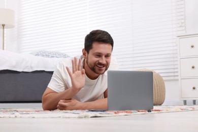 Happy man greeting someone during video chat via laptop
