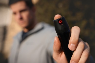 Photo of Man using pepper spray outdoors, focus on hand. Space for text