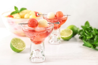 Glass of melon and watermelon ball cocktail on white wooden table