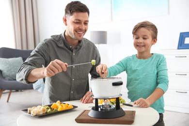 Photo of Father and son enjoying fondue dinner at home