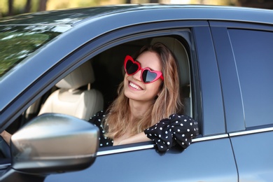 Photo of Young beautiful woman wearing heart shaped glasses in car