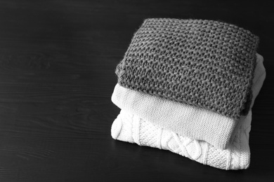 Photo of Stack of warm knitted clothes on table