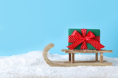Photo of Wooden sleigh with gift box on pile on snow. Space for text