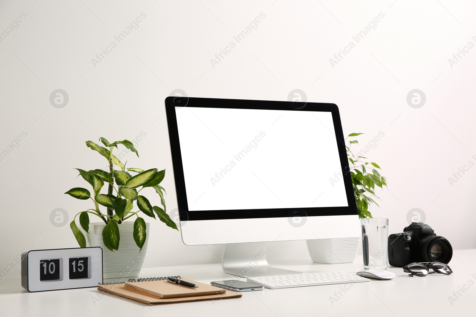 Photo of Comfortable workplace with modern computer on table near white wall. Space for text