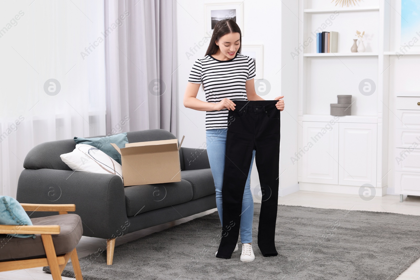 Photo of Happy woman with stylish black jeans at home. Online shopping