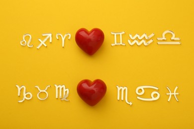 Photo of Zodiac compatibility. Signs with red hearts on yellow background, flat lay