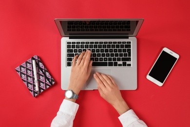 Photo of Woman using modern laptop at color table, top view