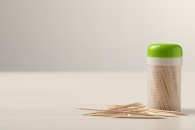 Disposable toothpicks and holder on white wooden background. Space for text