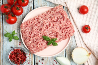 Photo of Raw chicken minced meat with basil, spices and vegetables on light blue wooden table, flat lay