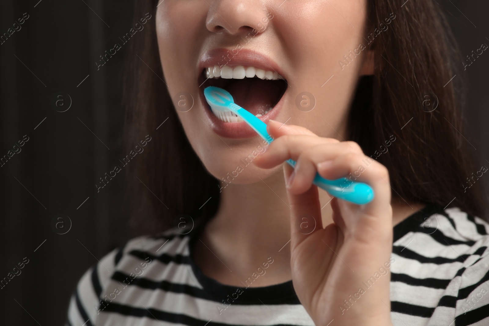 Photo of Woman brushing her teeth with plastic toothbrush in bathroom, closeup