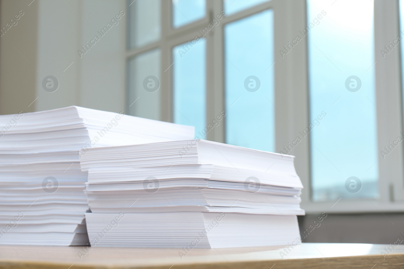 Photo of Stacks of paper sheets on wooden table indoors. Space for text