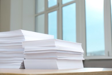 Stacks of paper sheets on wooden table indoors. Space for text