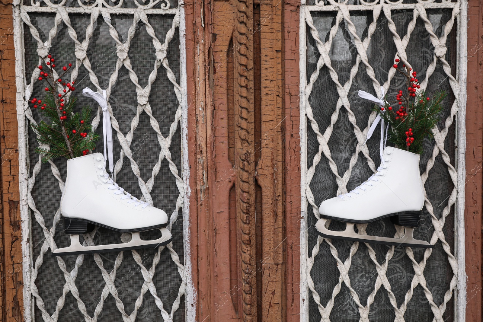 Photo of Pair of ice skates with Christmas decor hanging on old wooden door