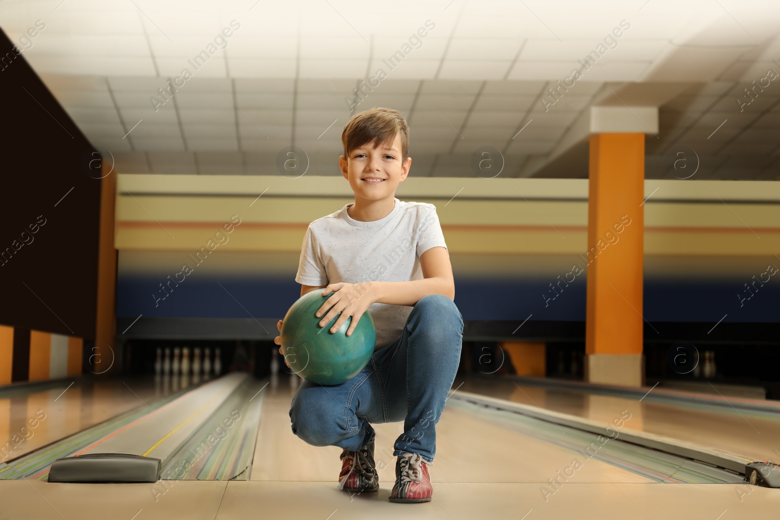 Photo of Preteen boy with ball in bowling club