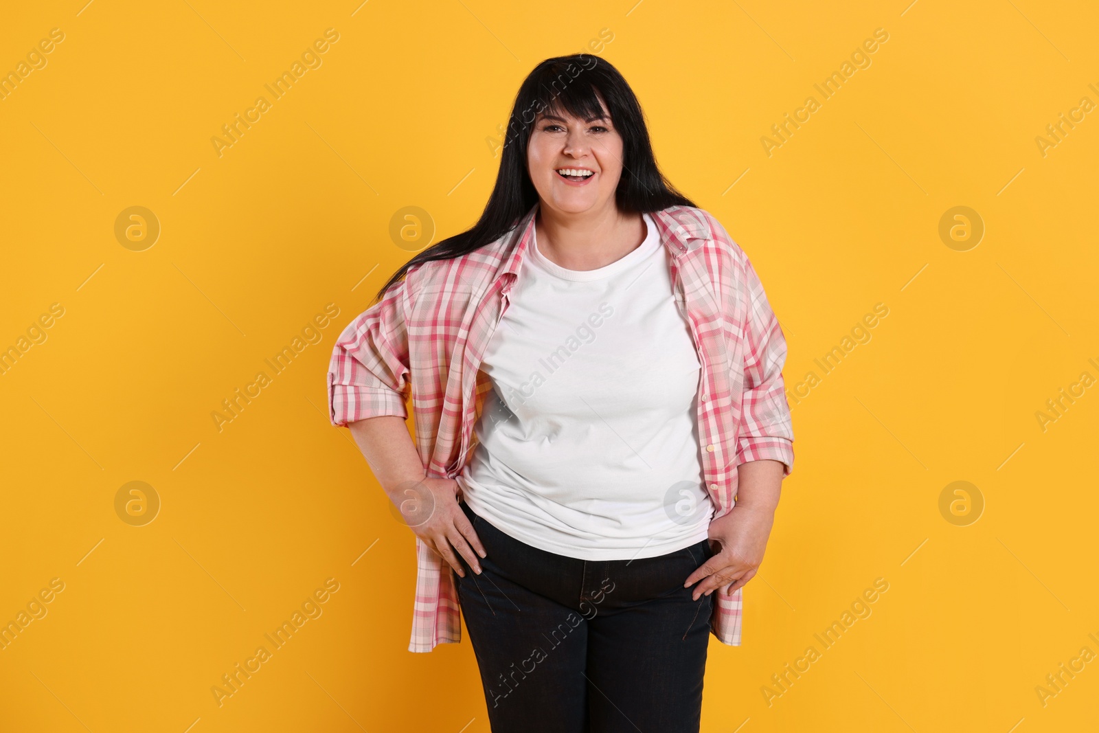 Photo of Beautiful overweight mature woman with charming smile on yellow background