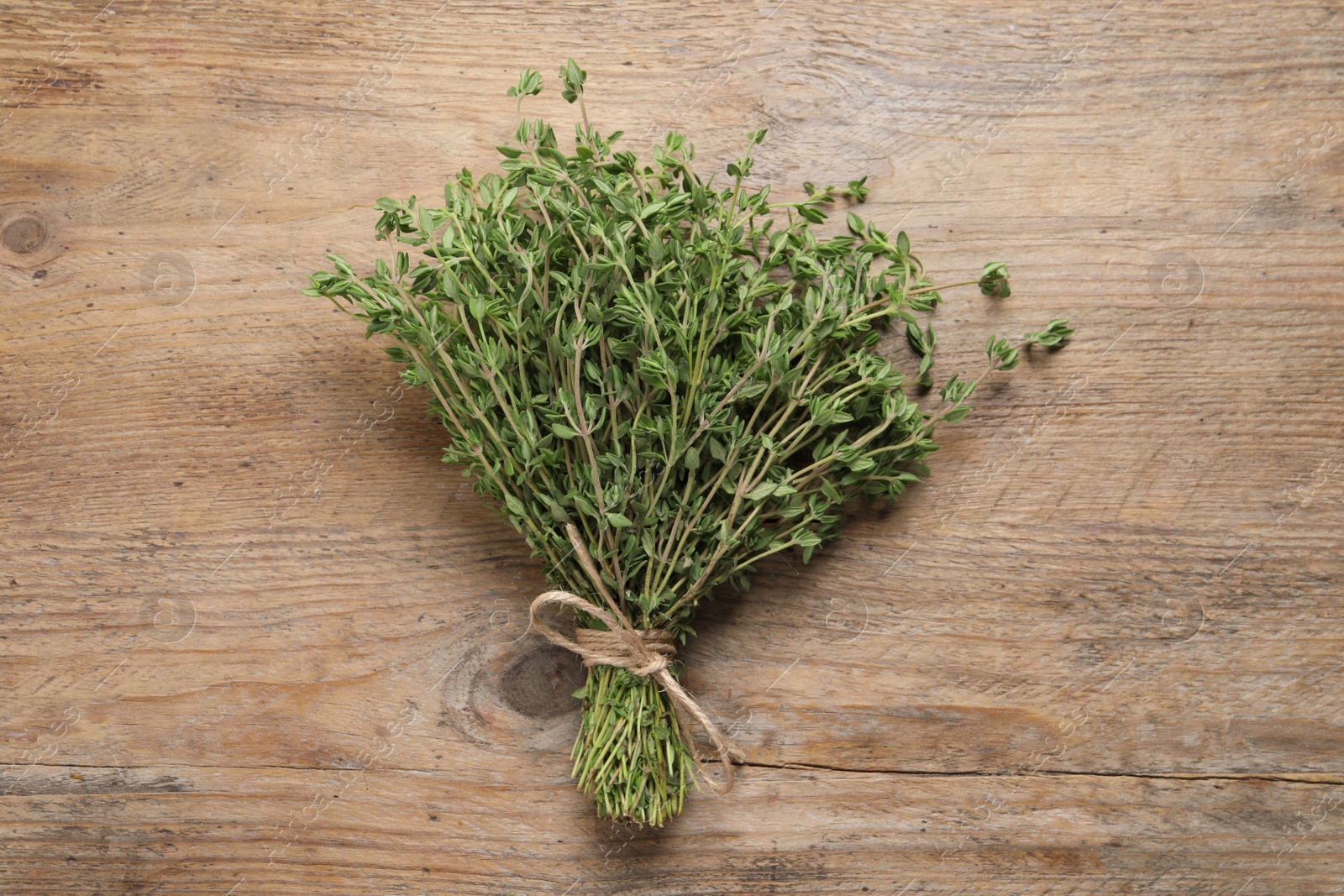 Photo of Bunch of aromatic thyme on wooden table, top view