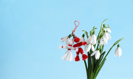 Photo of Traditional martisor and beautiful snowdrops on light blue background, space for text. Symbol of first spring day