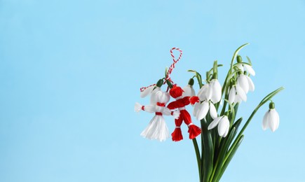 Traditional martisor and beautiful snowdrops on light blue background, space for text. Symbol of first spring day