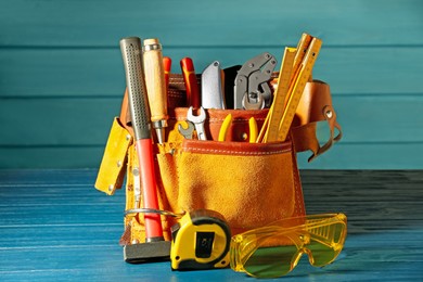 Photo of Belt with different tools on blue wooden table