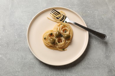 Photo of Heart made of tasty spaghetti, olives, cheese and fork on light grey table, top view