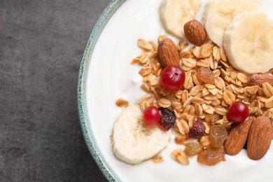 Photo of Bowl with yogurt, banana and granola on table, top view