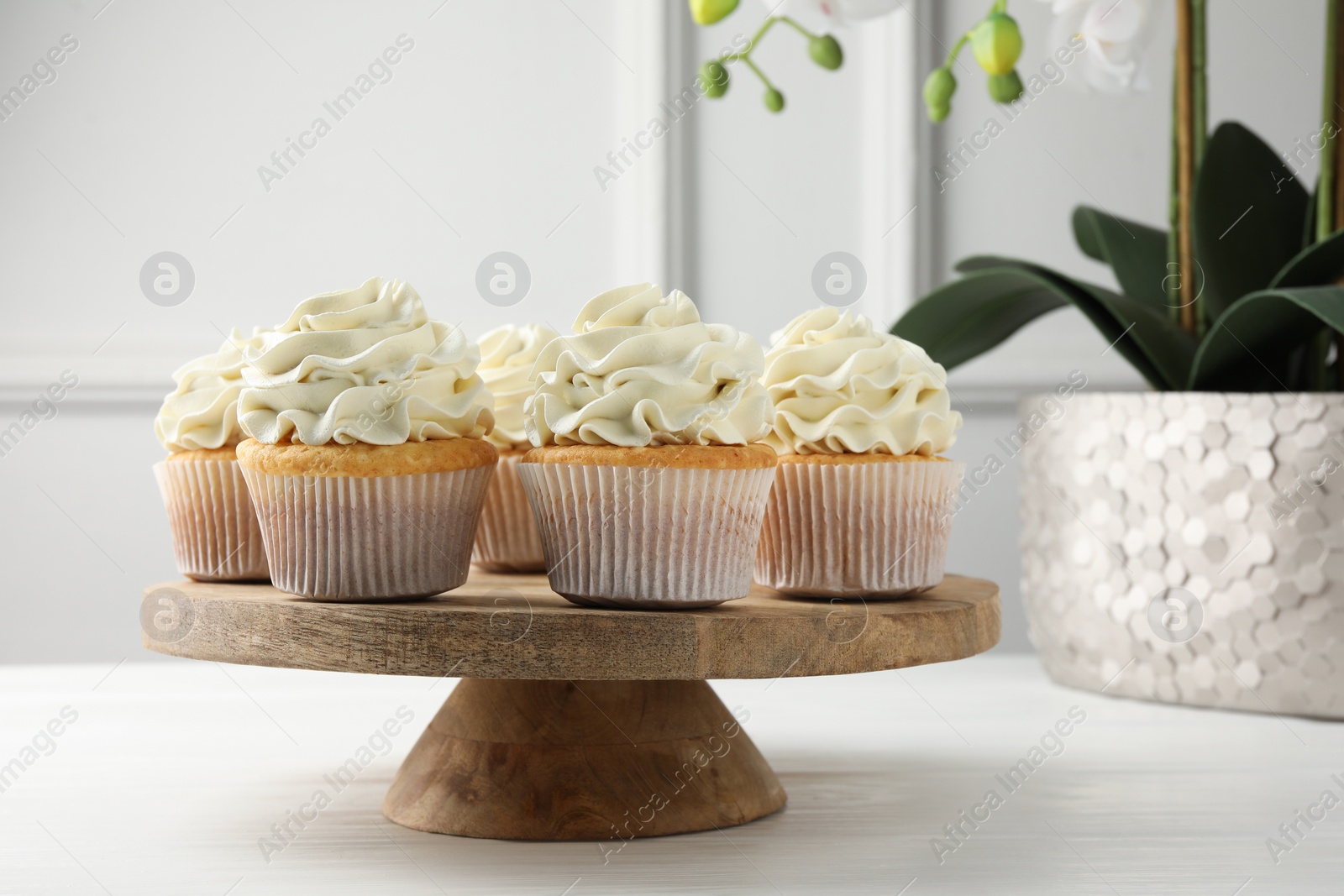 Photo of Tasty vanilla cupcakes with cream on white wooden table