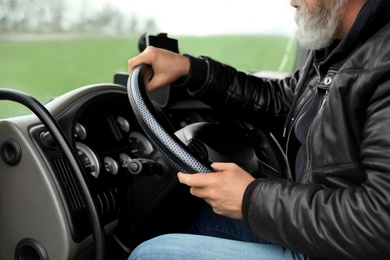 Photo of Mature driver sitting in cab of modern truck, closeup view