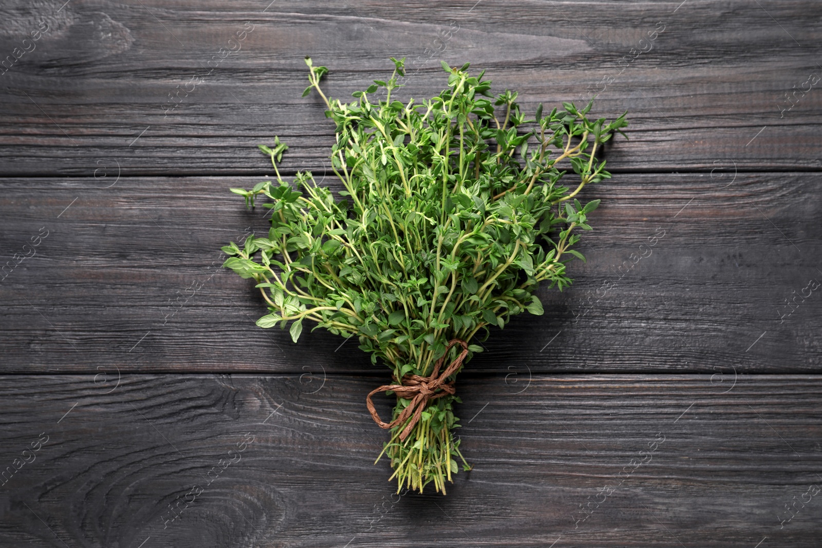 Photo of Bunch of aromatic thyme on wooden table, top view