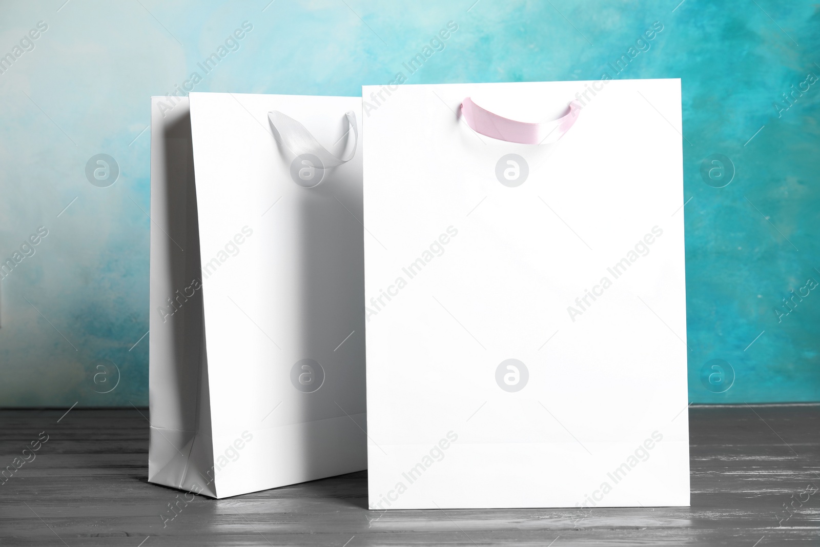 Photo of Paper shopping bags on table against color background. Mock up for design