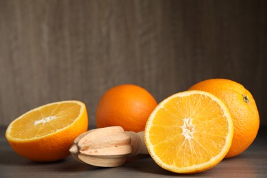 Photo of Fresh ripe oranges and reamer on wooden table