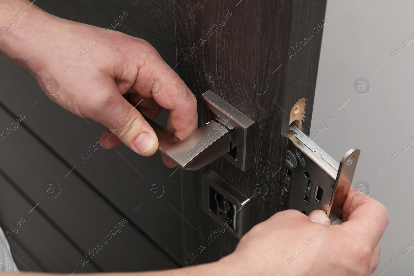 Photo of Handyman changing door handleset indoors, closeup view