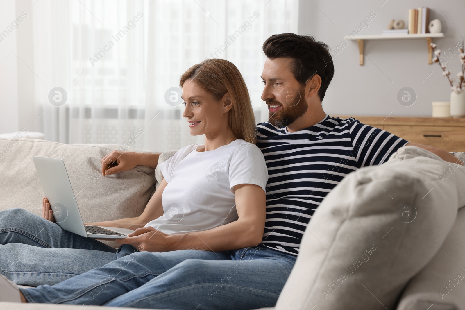 Photo of Happy couple with laptop on sofa at home